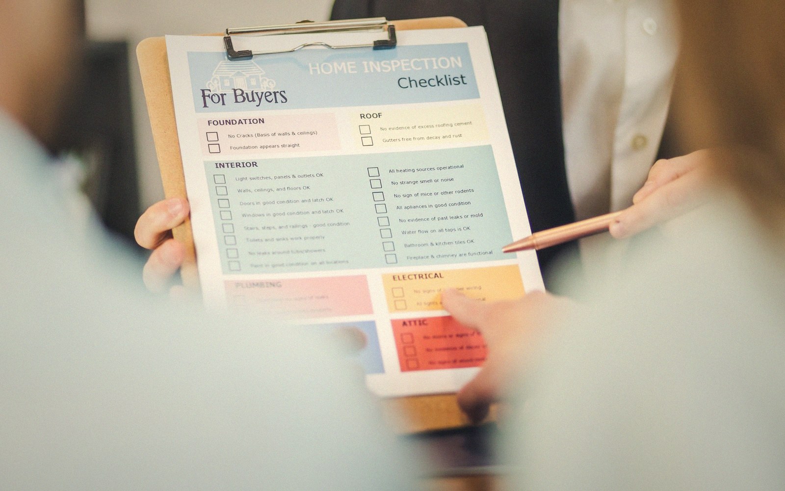 Hands hold a clipboard with a home inspection checklist for buyers while pointing with a pen
