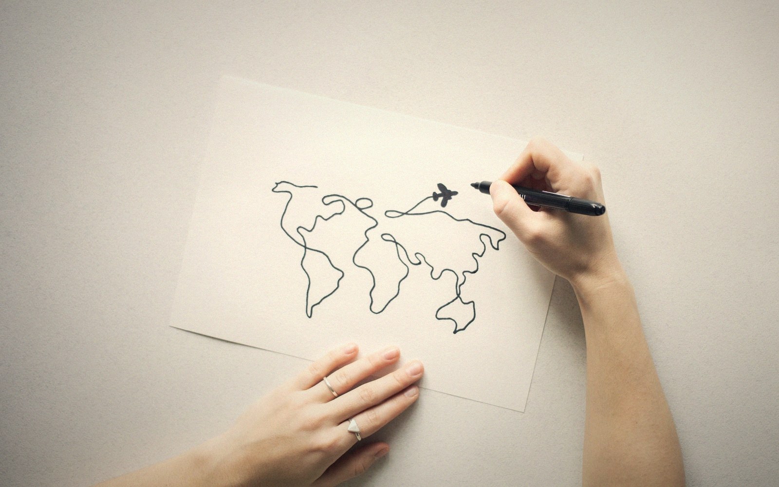 Hand drawing a world map outline with a small airplane in black pen