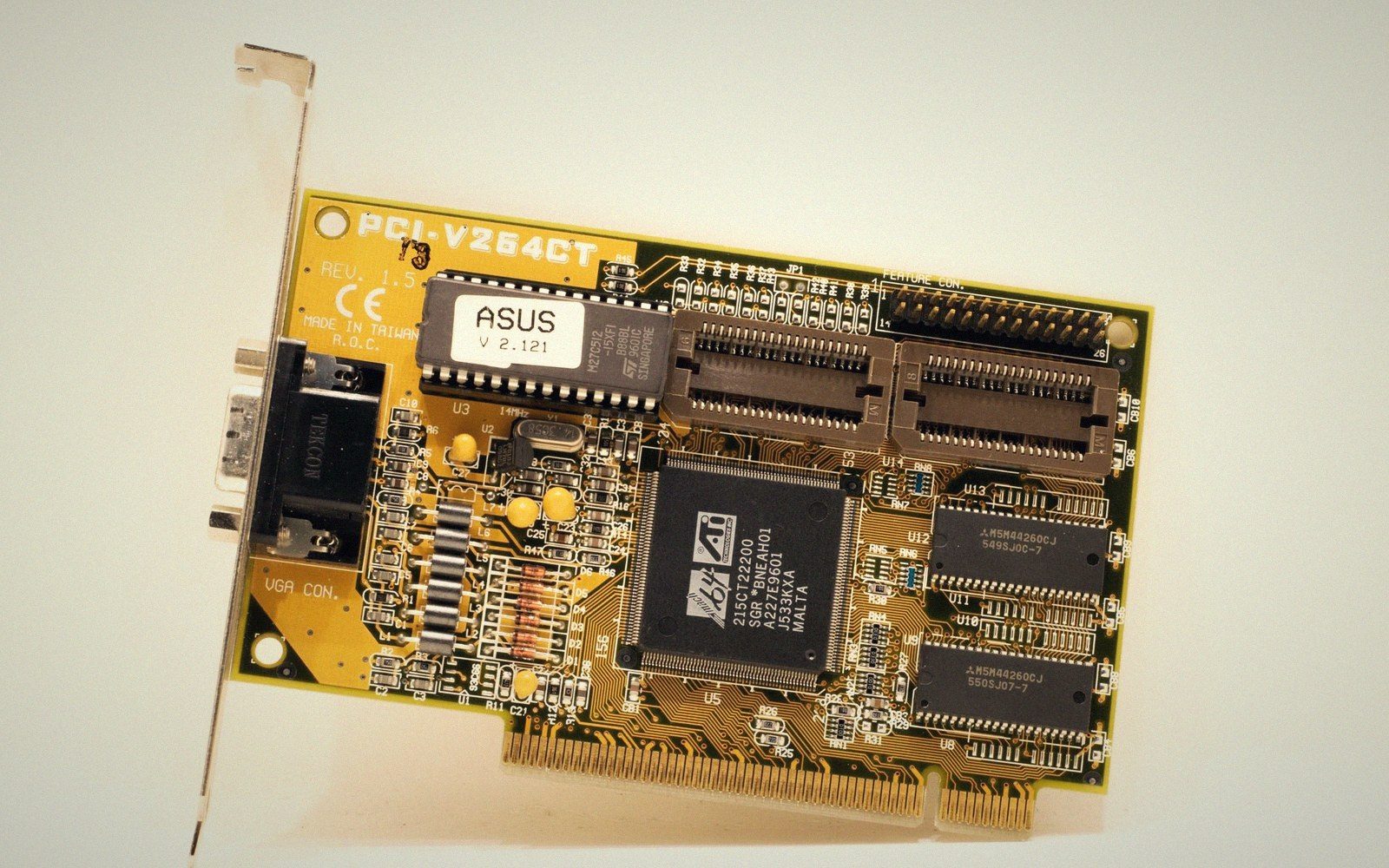 An Asus PCI-V264CT graphics card with VGA port, chips and connectors on a yellow circuit board