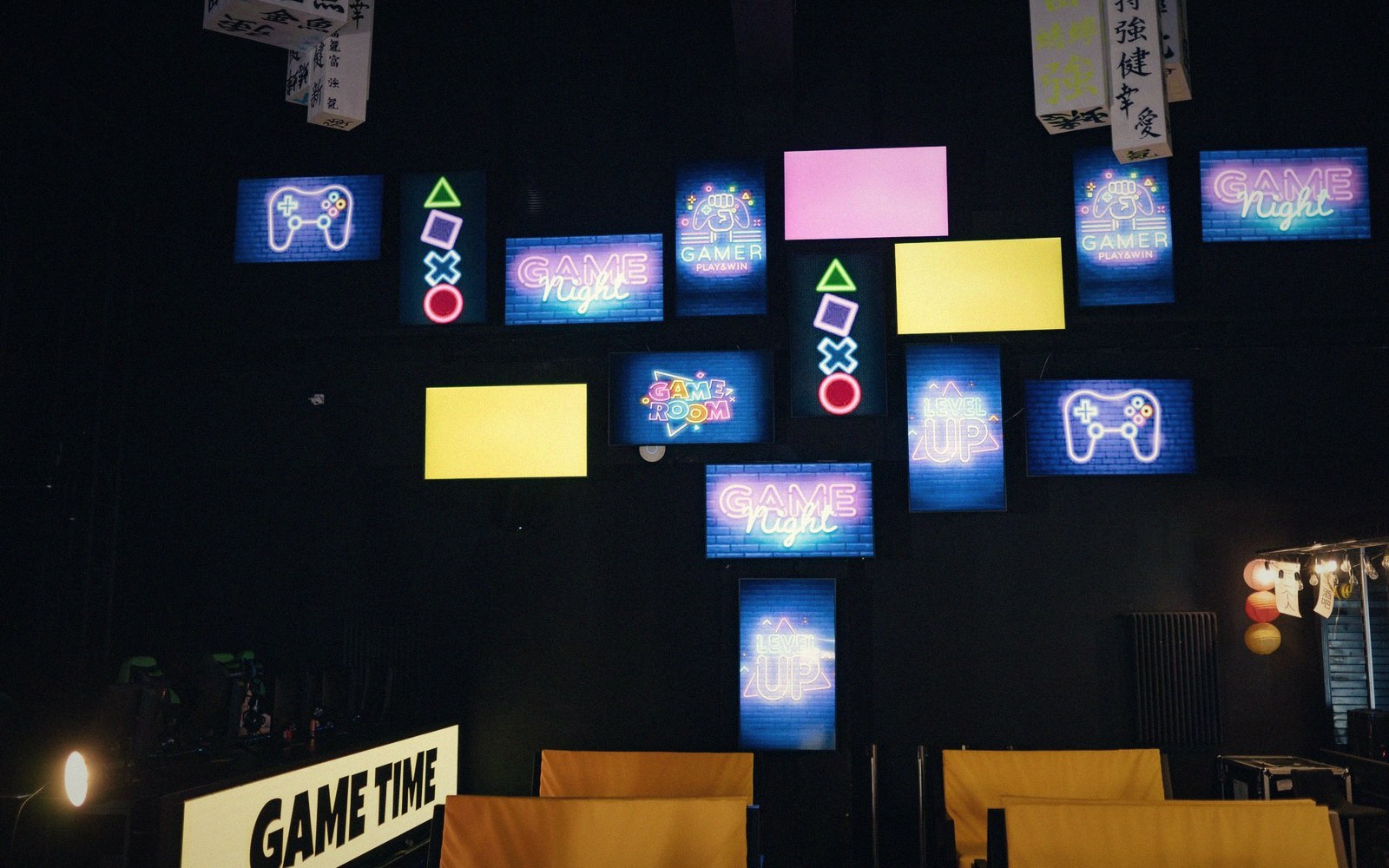 Neon signs reading "game night" and "game room" hang above rows of yellow deck chairs