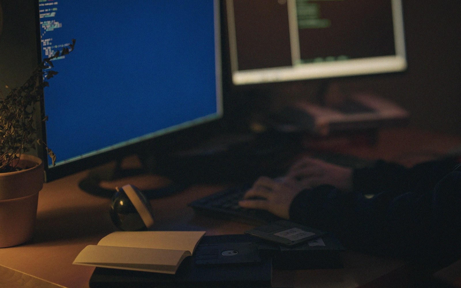 Two developers at a desk of monitors showing a grey-box level